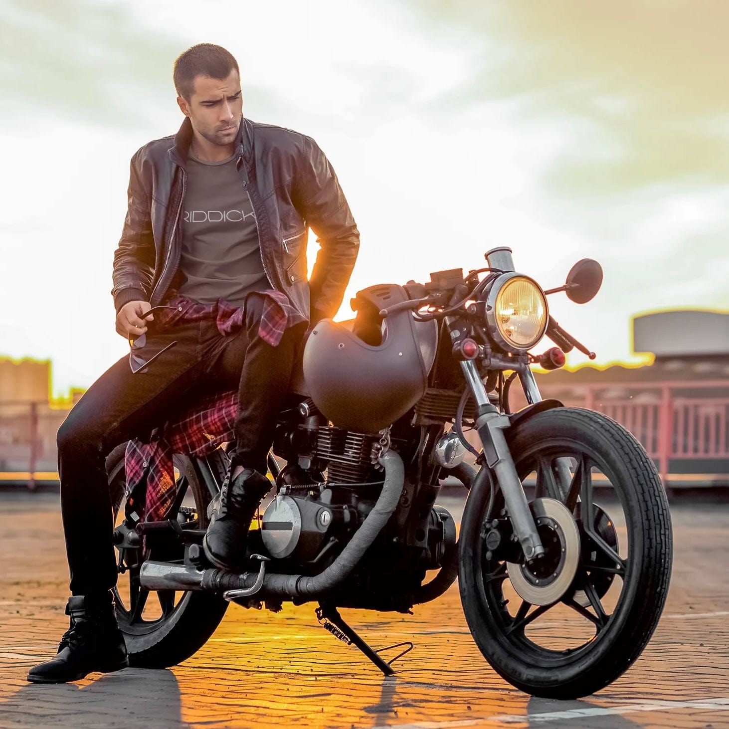 Male model wearing a signature baby blue RIDDICK T-shirt as he sits on his motorcycle.